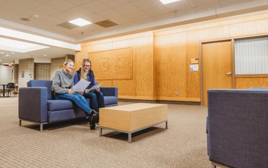 Two girls sitting on a couch in the student commons