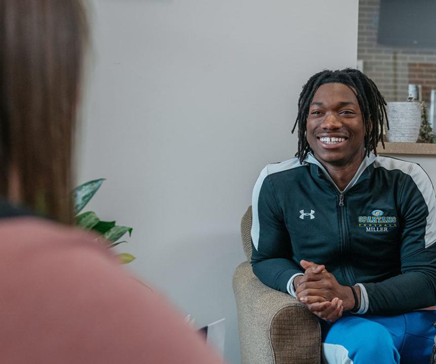 A smiling student sits in an office